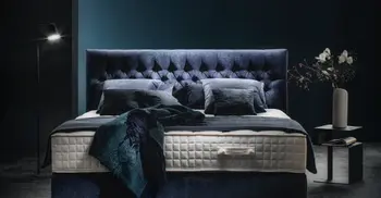 Doppelbett mit Samt-Bettbezügen in abgedunkelten Raum.