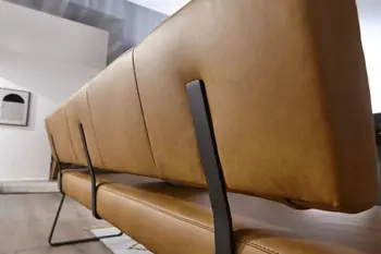 Rückseite einer cognac farbenen Rückenlehne einer Sitzbank, die Rückenlehne ist mit hochkanten schwarzen Metallstreben an der Bank befestigt.