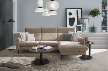 Beiges Ecksofa mit aufklappbaren Rückenlehnen und schwarzen Füßen in einem hellen Raum. 