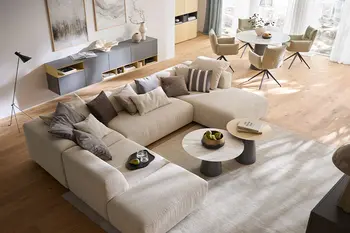 Modernes Apartement mit offenem Wohnbereich und beiger Wohnlandschaft und Essbereich mit rundem Esstisch und beigen Armlehnstühlen.