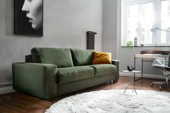 Grünes Zweisitzersofa in einem hellen Raum, mit einem gelben Kissen auf der rechten Seite.