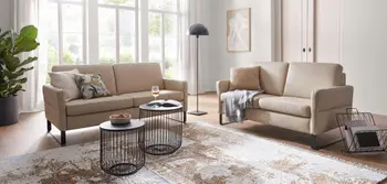Zwei beigefarbene Ledersofas im modernen Wohnzimmer mit dekorativen Kissen, Designer-Beistelltischen aus schwarzem Metall, stilvollem Teppich im Vintage-Look und gemütlicher Wohlfühlatmosphäre – elegantes Sofa-Set für stilvolle Wohnräume.