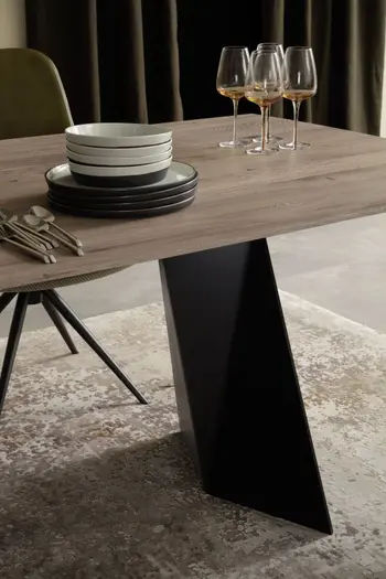 Designer Esstisch mit Tischplatte aus Massivholz und schwarzem Metall Fußgestell, auf dem Tisch stehen Weingläser und weiße und schwarze Teller und Besteck.