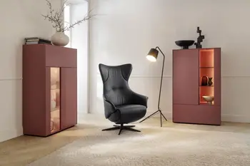 Zwei moderne rote Vitrinen mit beleuchteten Glaselementen in einem hellen Raum mit Stehlampe und Relaxsessel.