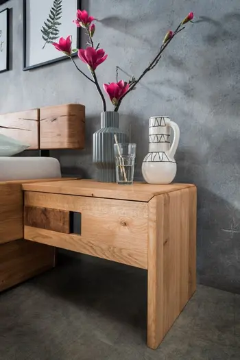 Massivholz Nachtkonsole, die am Bett befestigt ist und auf der zwei Vasen und ein Glas mit Blumen stehen.
