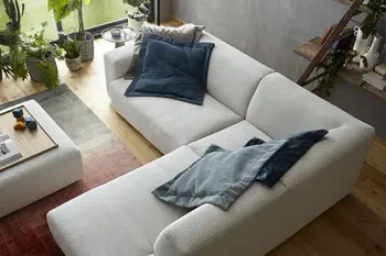 Beiges Cord Ecksofa in einem hellen Raum dekoriert mit Kissen in Beige und blau.