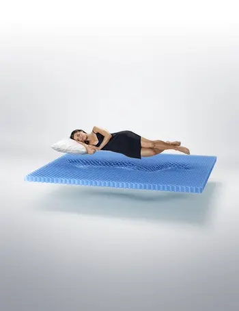 Eine Frau schläft entspannt auf einer schwebenden IntelliGel®-Matratze von Svane®. Die Struktur der Matratze passt sich perfekt an ihren Körper an und bietet ergonomische Unterstützung für höchsten Schlafkomfort.
