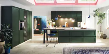 Waldgrüne Landhauskueche mit Kuecheninsel unter großem Dachfenster