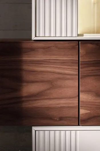 Detailansicht einer Wohnwand, die aus Elementen in Nussbaum und weißem Lack besteht.