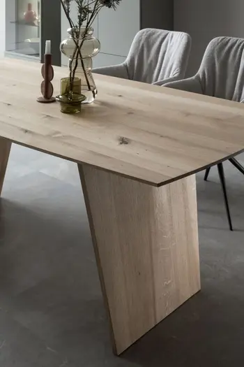 Moderner Massivholz Esstisch mit Fußgestell aus Massivholz, auf dem 2 Vasen und ein Kerzenständer stehen.