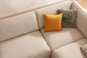 Vogelperspektive auf Ecksofa mit beigem Stoffbezug, dekoriert mit gelbem und grünem Kissen.