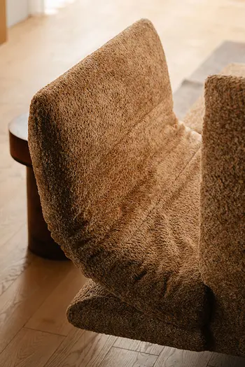 Hochgeklappte Armlehne eines braunen Stoffsofas.