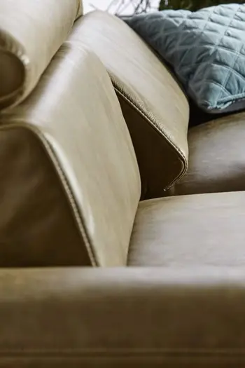 Sitzfläche eines grünen Ledersofas, bei dem eine Rückenlehne etwas nach vorne geklappt ist.