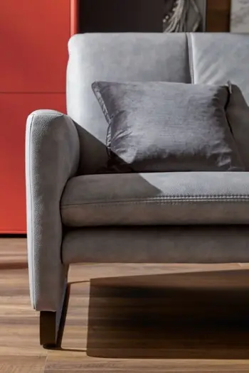 Graues Ledersofa mit schwarzen Kufen.