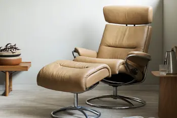 Stressless Tokyo Relaxsessel mit verstellbarem Kopfteil in der Farbe Paloma Almond, auf einem verchromten Untergestell, in einem modernen Wohnraum mit Holz- und Dekoelementen.
