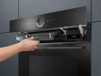 Backofen von Bosch, das Bedienfeld ist nach oben geklappt und eine Hand entnimmt den Filter.&nbsp;