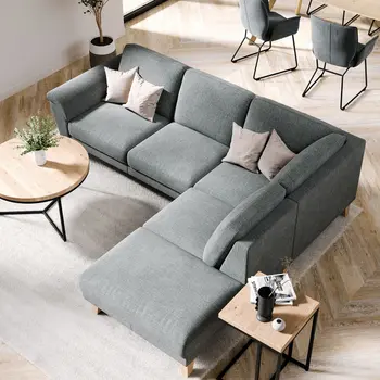 Graues Ecksofa dekoriert mit rosa Kissen dazu ein Couchtisch und Beistelltisch mit schwarzem Metallgestell und Tischplatte aus Holz.