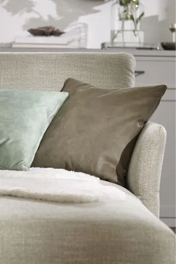 Hellgrüner Longchair eines Ecksofas, das mit Kissen und Decke dekoriert ist.