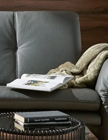 Graues elegantes Ledersofa, das eine senkrechte Ziernaht im Rückenkissen hat.