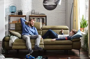 Grünes Ledersofa auf dem ein Mann sitzt und daneben ein Junge liegt.