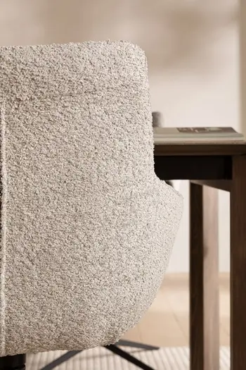 Ansicht der Rückenlehne eines grauen Schalenstuhls von hinten, der Stuhl steht an einem dunklen Esstisch aus Holz.