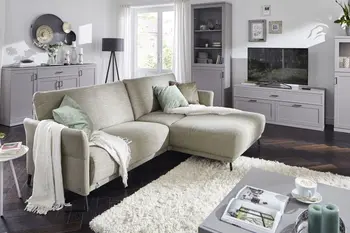 Hellgrünes Ecksofa mit großen Rückenkissen in einem gemütlichen Wohnzimmer.