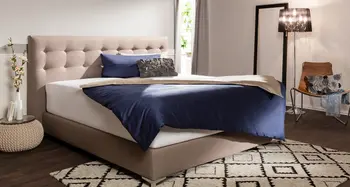 Schlafzimmer mit Polsterbett, dunkler Decke und Stehlampe.