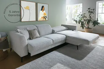 Ecksofa in hellgrauem Stoff mit Liegefunktion bei Longchair in hellem Wohnzimmer - inklusive Garantiehinweis.
