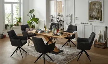 Sie sehen ein Esszimmer mit Tisch in Eiche Mittelfuß in Eiche und dunklen Armlehnstühlen 