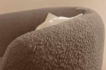 Seitliche Aufnahme eines braunen Sessels mit niedriger Rückenlehne und runder Form.