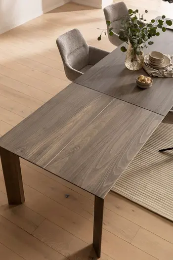 Esstisch in dunklem Holz, der mit einer Platte verlängert wurde.