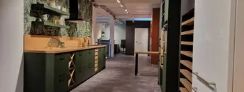 Moderne Küche in einem matten dunklen Grün, mit Holzarbeitsplatte und Pflanzenmustertapete.