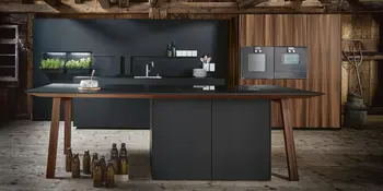 Inselkueche mit hoelzernen und anthrazitfarbenen Elementen sowie Kraeutertoepfen und Einbaugeraete.