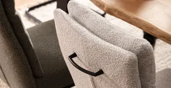 Freischwinger Stuhl in grau mit schwarzem Metallgriff an der Rückenlehne.