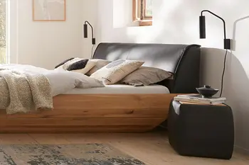 Gemütliches Schlafzimmer mit Doppelbett und passendem Nachttisch in schwarzem Leder.