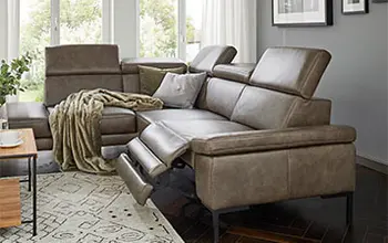 Olivgrünes Ledersofa mit ausgeklappter Fußstütze.