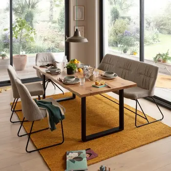 Helles gemütliches Esszimmer mit grauen Stühlen und grauer Sitzbank um einen Holz Esstisch.