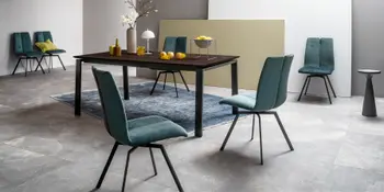 Dunkler Holzesstisch mit petrolfarbenen Polsterstuehlen im Esszimmer.