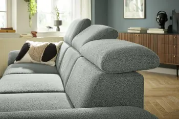 Grünes Sofa mit klappbaren Kopfstützen in einem hellen Raum.