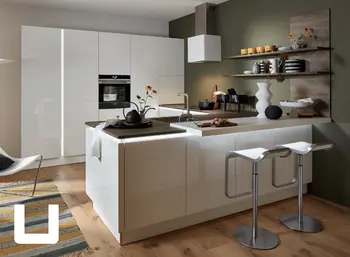 U-förmige Küche mit Hochglanzfronten in Weiß. Akzente bilden die beleuchteten Griffmulden und der Tresenbereich mit zwei Hockern. Arbeitsplatte sowie die Regale an der Wand sind in Holzoptik.&nbsp;