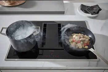 Dunst von einem Kochtopf und einer Pfanne wird von Muldenlüfter aufgesaugt