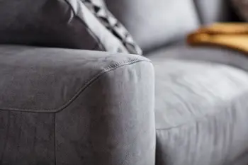Armlehne eines grauen Sofas mit Stoffbezug aus der Nähe.
