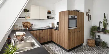 Hoelzerne Winkelkueche mit Dachschraege und anthrazitfarbener Arbeitsflaeche.