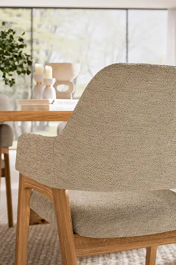 Detailaufnahme von Rückenlehne eines Armlehnstuhls in beigem Stoff.