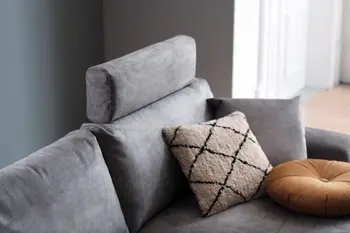 Graues Sofa mit Stoffbezug, bei dem an einer Rückenlehne eine Kopfstütze angebracht ist.