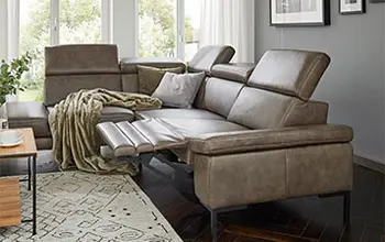 Olivgrünes Ledersofa mit ausgezogener Fußstütze in Seitenansicht.