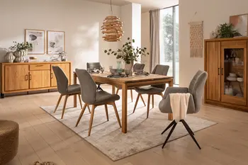 Moderner gedeckter Massivholztisch mit Blumenvase und um den Tisch herum mit grauen Schalenstühlen mit und ohne Armlehne.