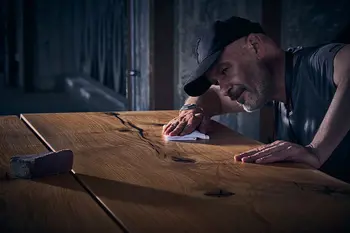 Mann bei der Herstellung eines Design Esstisches aus Massivholz.