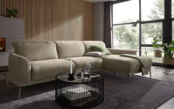 Modernes Ecksofa in Beige mit filigranen Metallfüßen vor Holzlamellen-Wand – stilvolles Wohnzimmer mit schwarzem Couchtisch, dunklem Teppich und großen Panoramafenstern für gemütliches Wohnambiente.