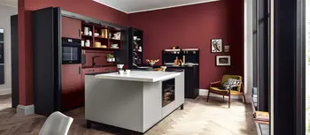 Hellgraue Kuecheninsel mit dunkler Kuechenzeile in rotgestrichener Kueche in moderner Wohnung.